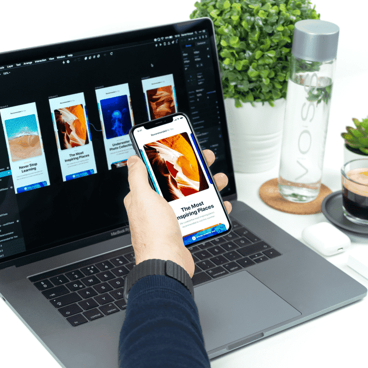 Person holding mobile phone in front of a laptop with the same design on both devices