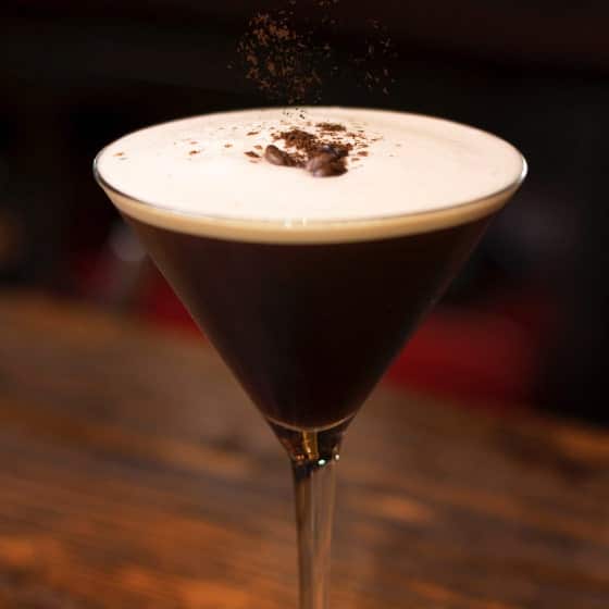 An Espresso Martini cocktail on a table and a dark background