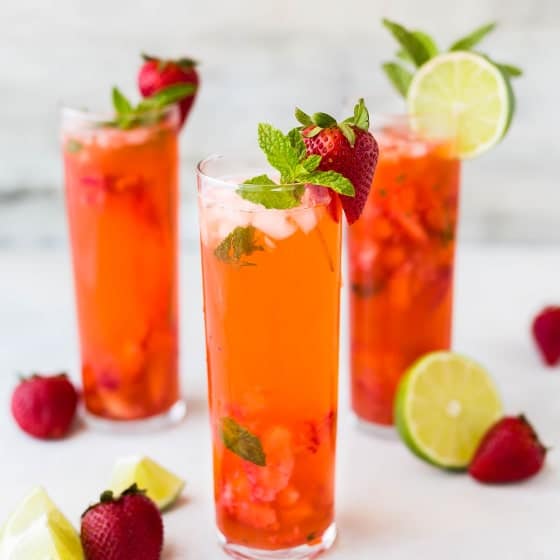 Pumpkin spice margarita on a bright table with limes and strawberries as a garnish