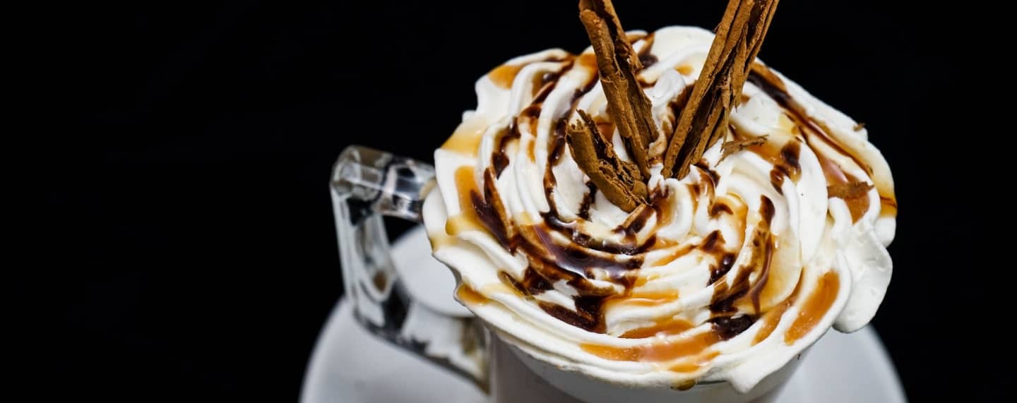 Boozy Christmas Coffee Cocktail with festive toppings in a mug on a dark background